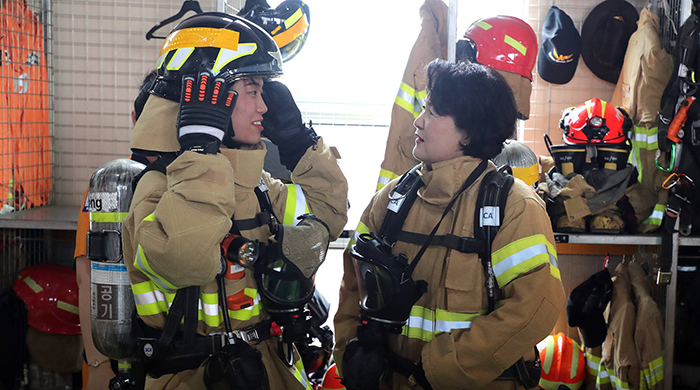 First lady Kim Jung-sook (right) listens to an explanation about the firefighting gear she has on, at a fire station in Hwaseong, Gyeonggi Province, on Aug. 8.